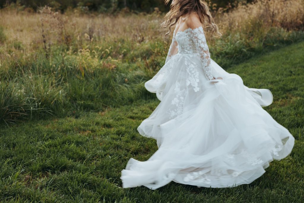 bride spinning in wedding dress in a field