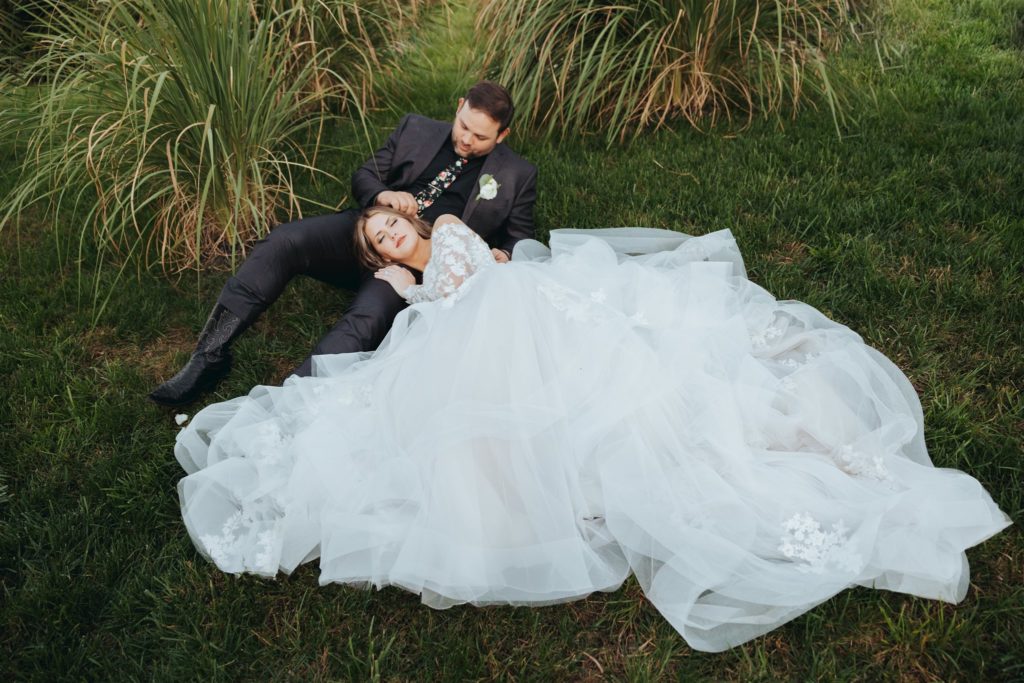 bride and groom laying down in a field