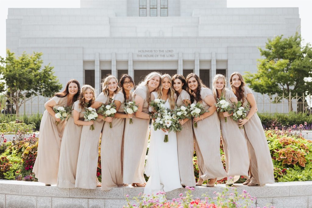 bride with bridesmaids in front of the temple at Draper Temple in Utah