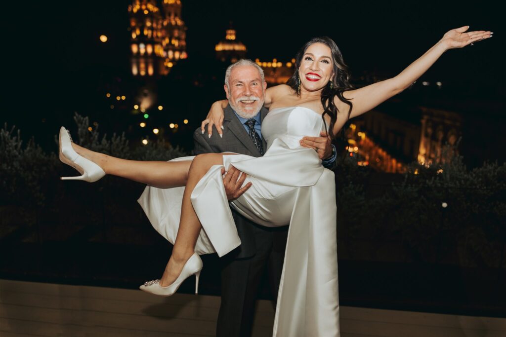 father of the bride holding the bride in his arms laughing in morelia mexico