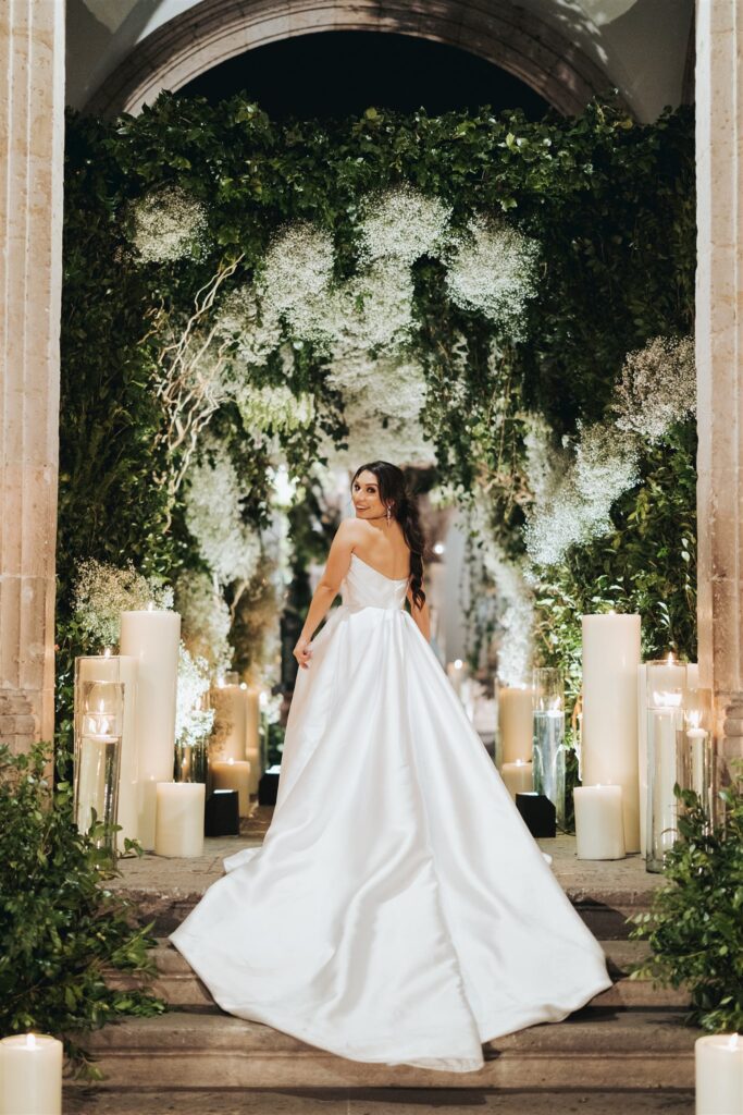 bride standing in front of wedding reception floral arch with lights and candles in morelia mexico