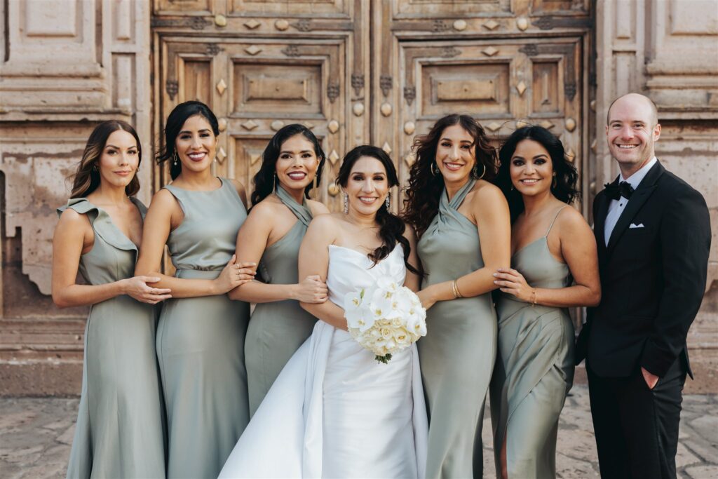 bride with bridesmaids in front of cathedral