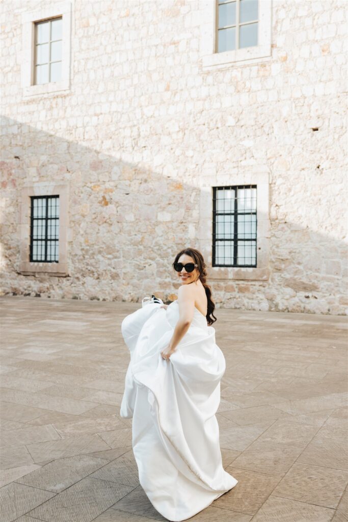 bride running in wedding dress with sunglasses