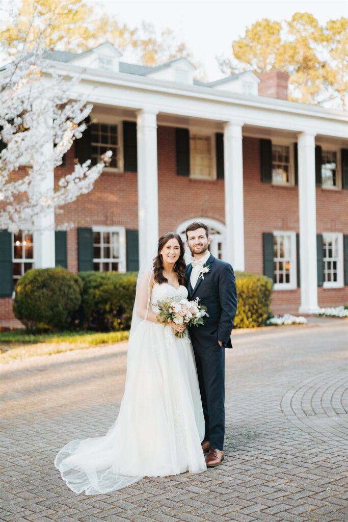 bride and groom posing in front of historic home