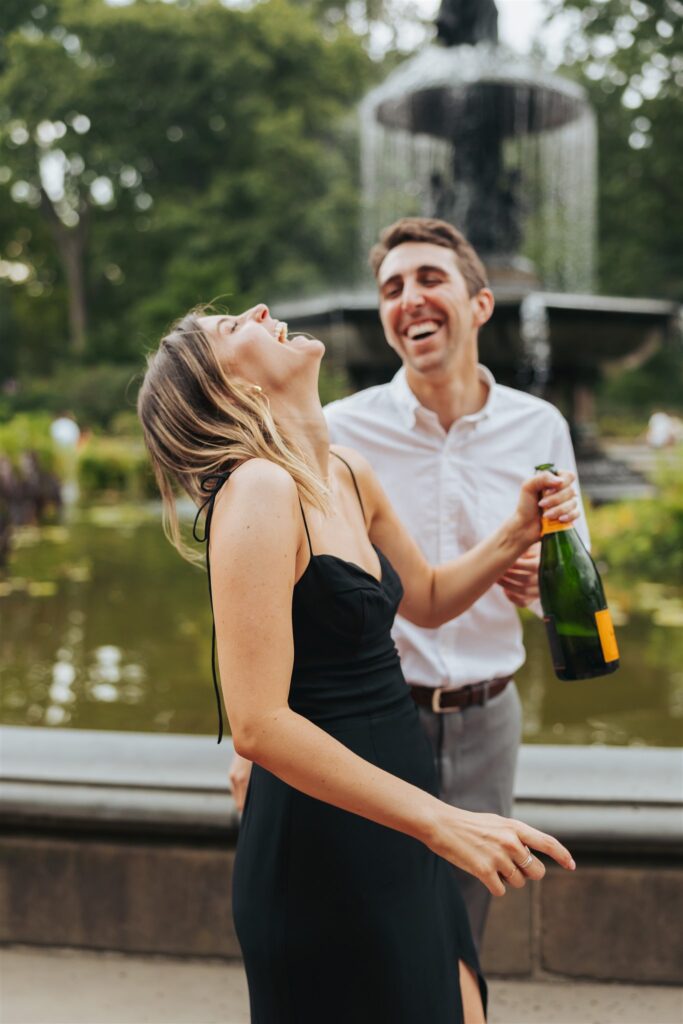 engaged couple popping champagne at central park in new york city