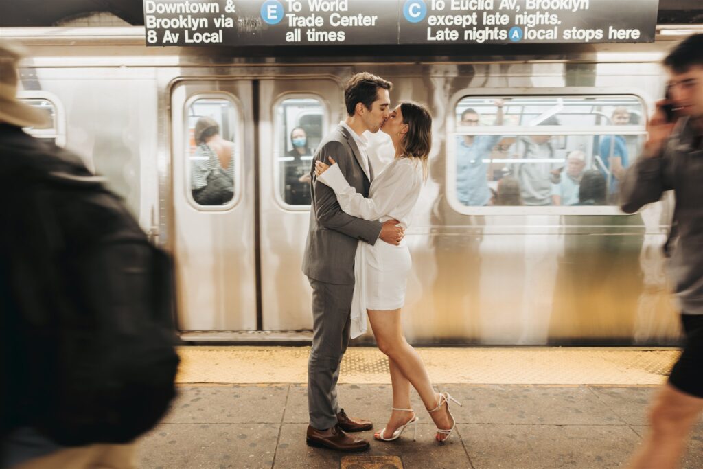 engaged couple kissing in front of a subway in new york city