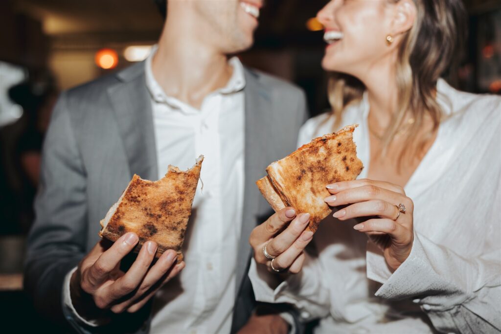 engaged couple eating pizza at pizza shop in new york city
