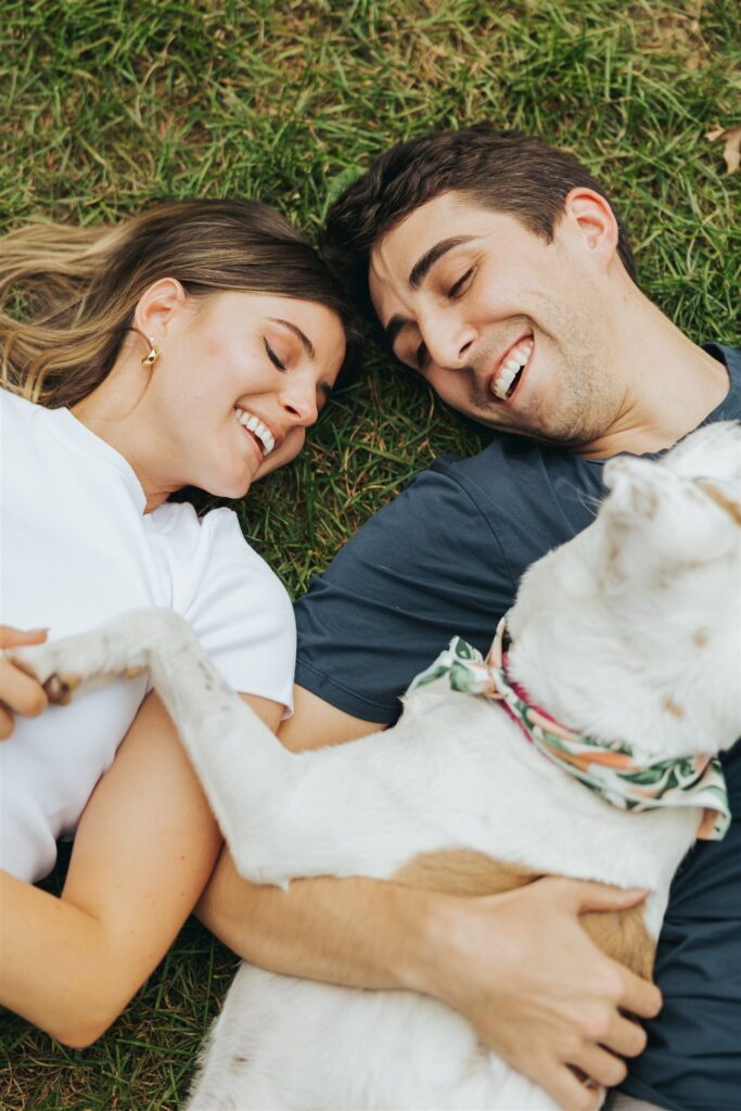 man and woman cuddling with dog at central park