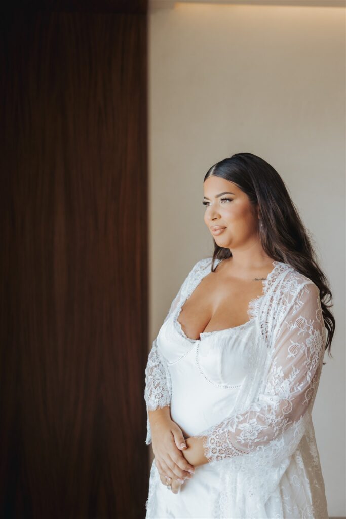 bride in lace white gown and robe getting ready for wedding