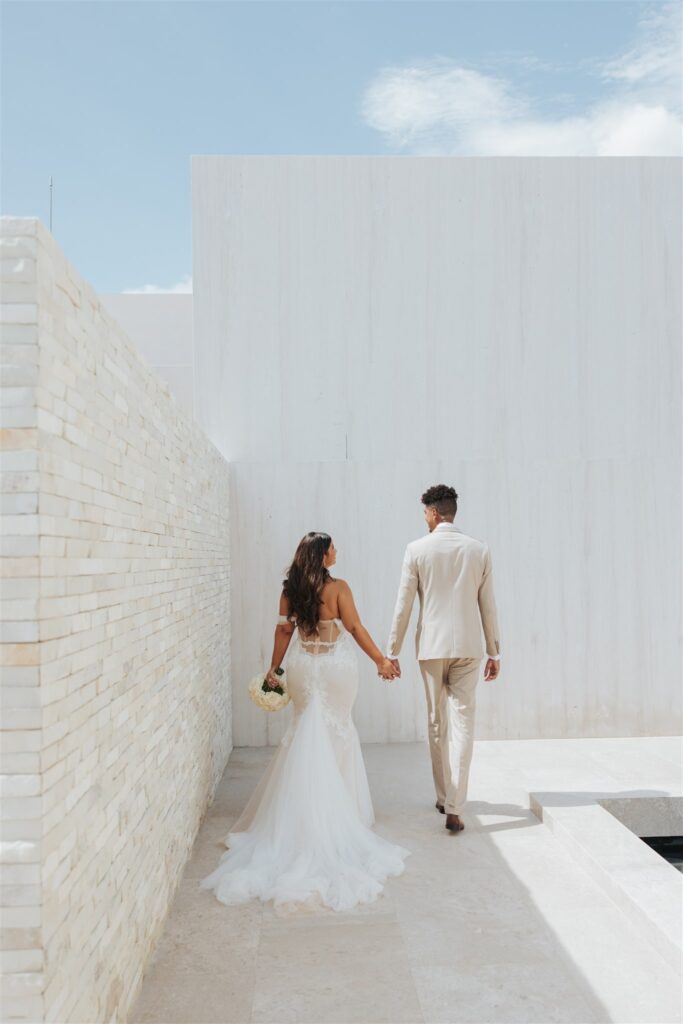 bride and groom in front of a tan brick wall nobu hotel los cabos