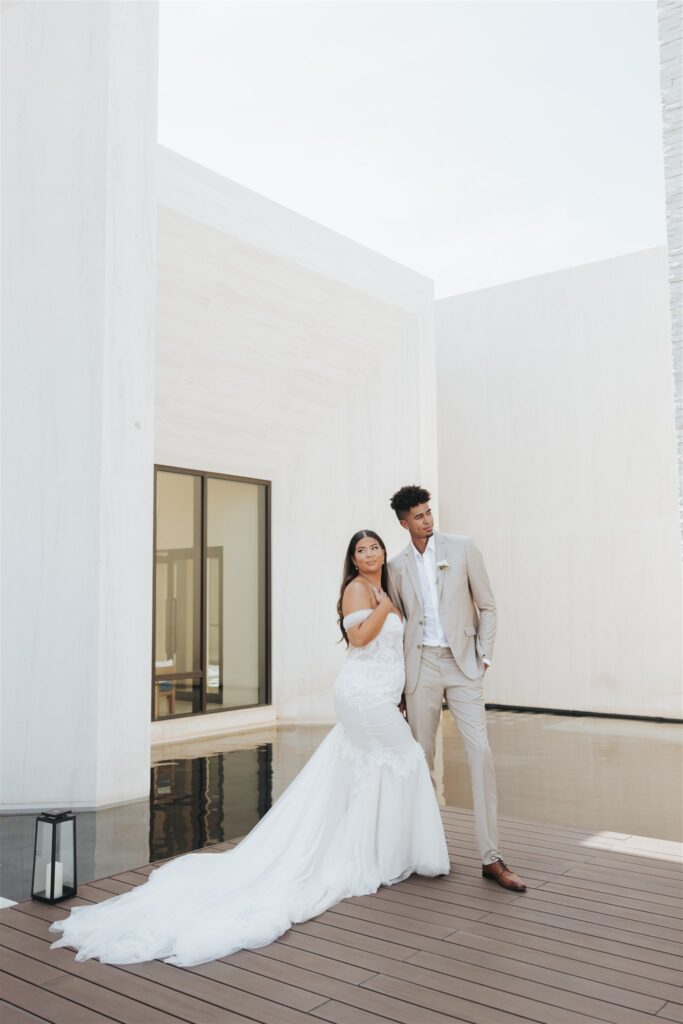 bride and groom posing in front of white wall los cabos luxury wedding