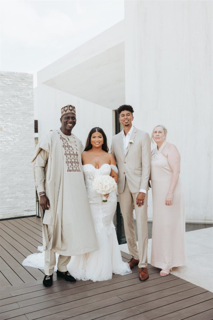 bride and groom with family posing in front of white wall