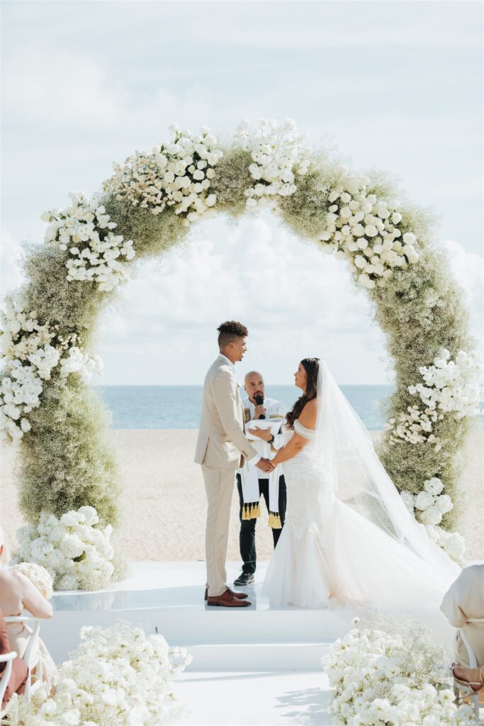 bride and groom wedding ceremony with floral arch at the beach in los cabos