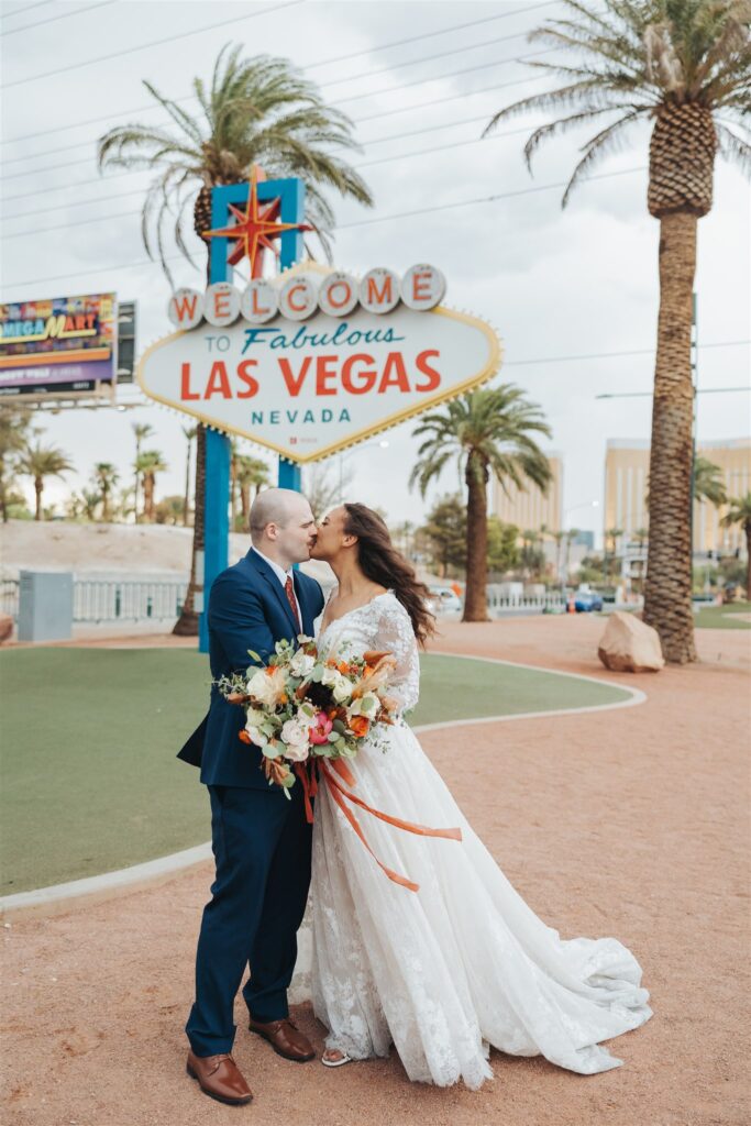 bride and groom kissing in the road in front of las vegas sign