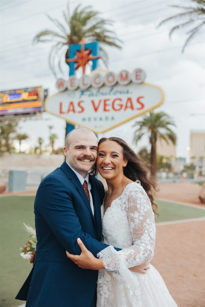 bride and groom walking in the road in front of las vegas sign