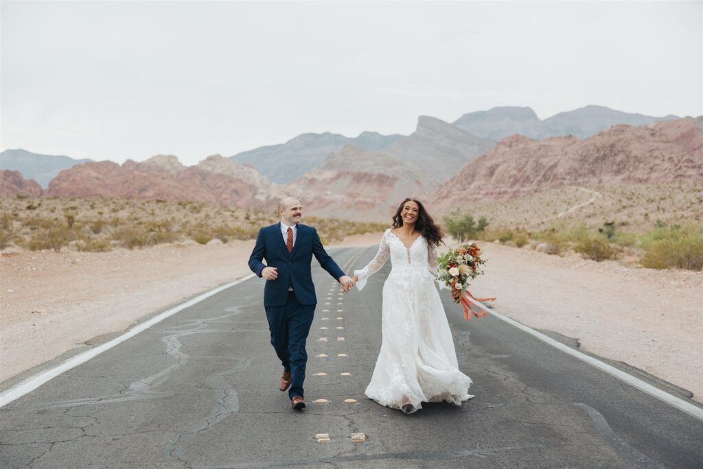 bride and groom walking in the road in the dessert