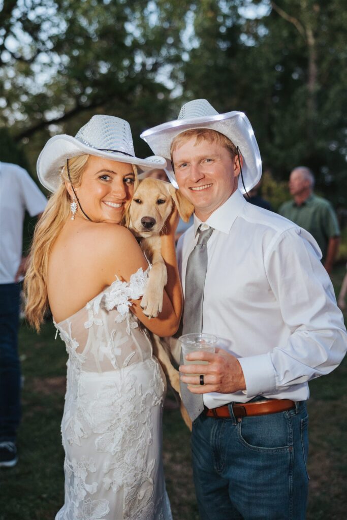 bride and groom with cowboy hats and puppy