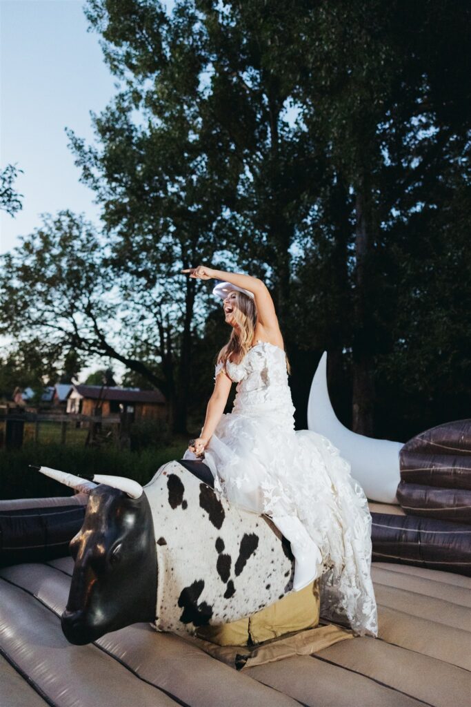 bride riding mechanical bull at aurora, oregon wedding