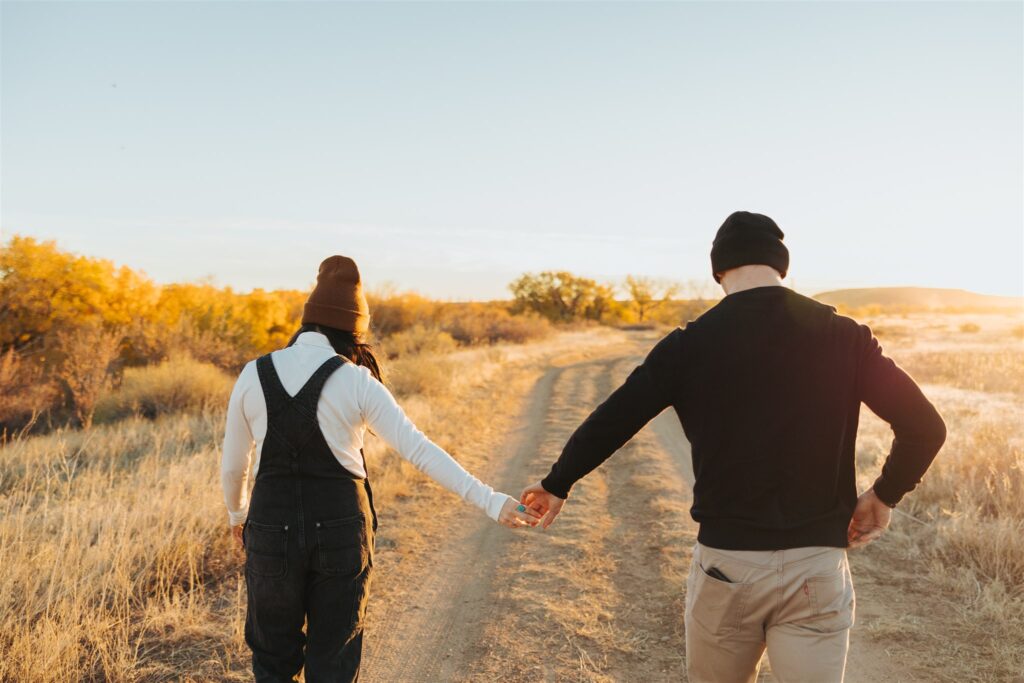 couple holding hands and walking in a field in the fall