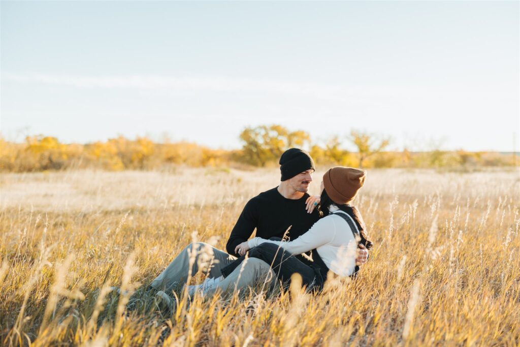 couple sitting in a field in the fall in colorado