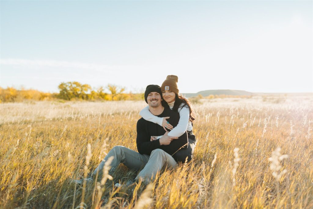 couple sitting in a field in the fall