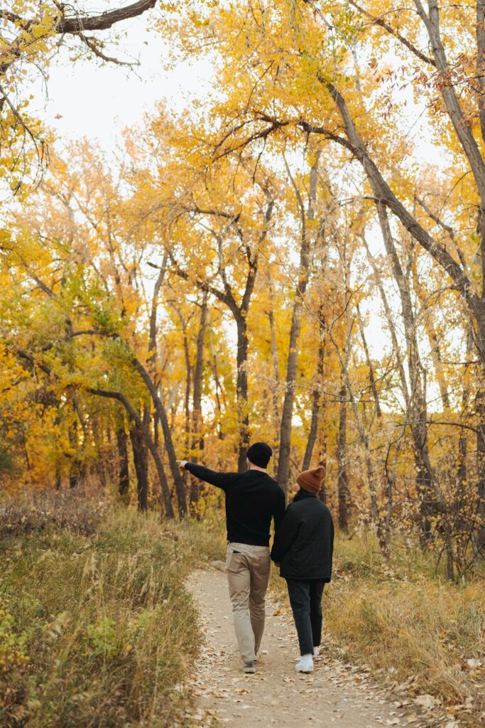 couple holding hands and walking in the woods in the fall in colorado