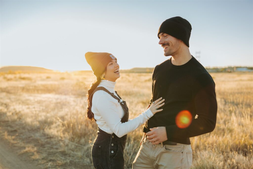 couple laughing in a field in the fall engagement session in colorado