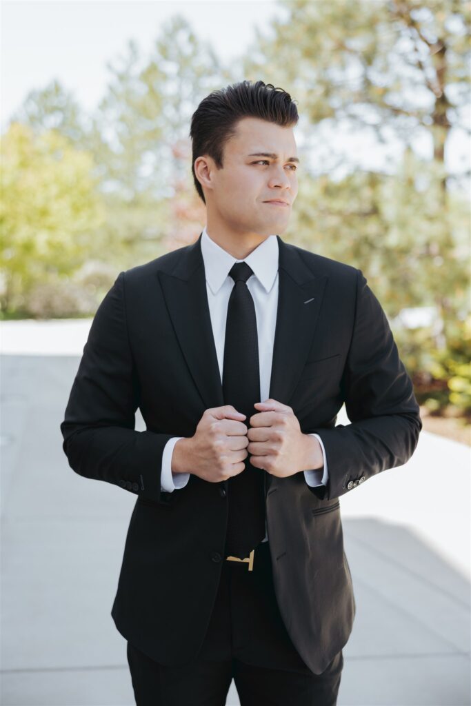 groom in black suit getting ready for wedding